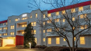 A multi-story hotel with a flat facade, balconies, and a red accent on the roof.