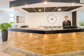 A hotel reception desk with a clock, a sign reading 'HOTEL NEWTON', and a receptionist.