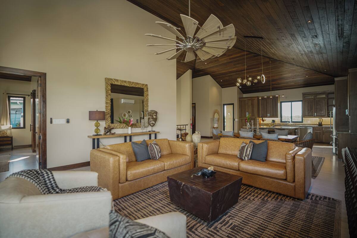 A spacious living room with a large sectional sofa, a coffee table, and a unique ceiling fan.