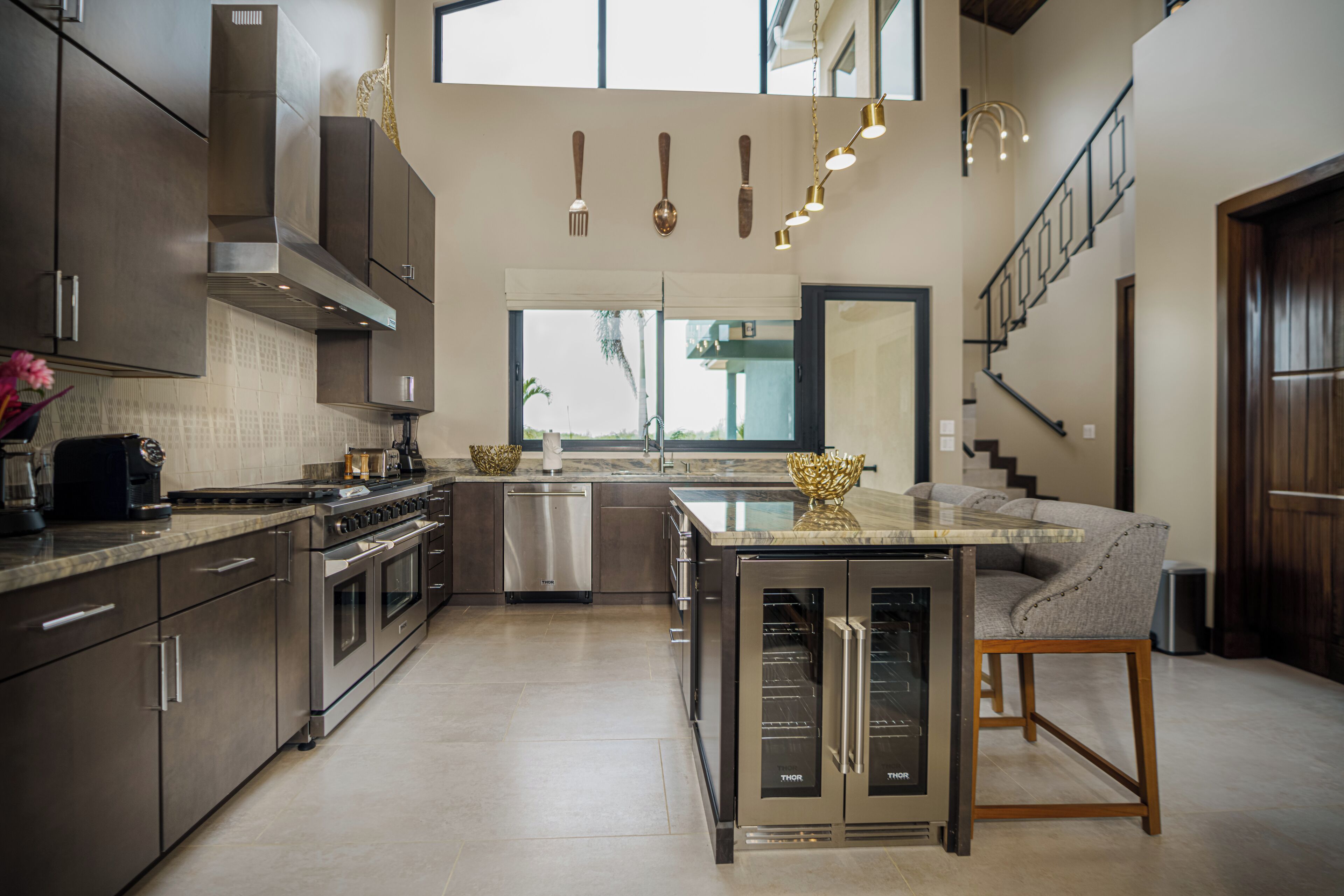 Una cocina moderna con electrodomésticos de acero inoxidable, una isla central y un comedor con sofá.
