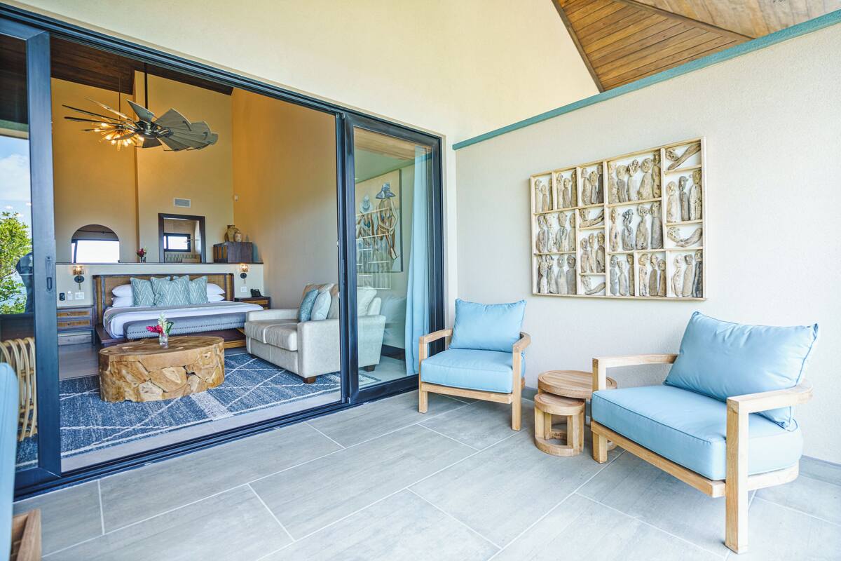 A modern living room with a sofa, chairs, and a coffee table. There is a large window with a view of the outside.
