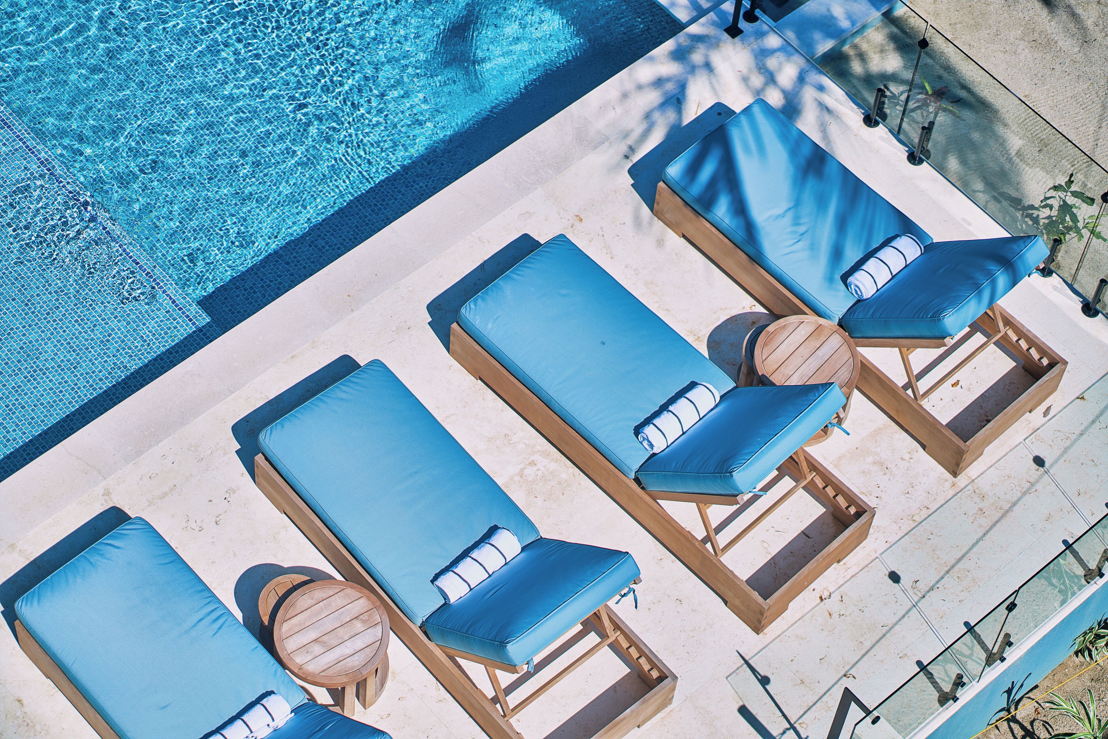 An aerial view of a poolside area with lounge chairs and a wooden table.