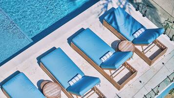 An aerial view of a poolside area with lounge chairs and a wooden table.