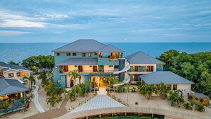 A multi-story resort with a central courtyard, multiple balconies, and a view of the ocean. - Prana Maya Island Resort (Placencia)