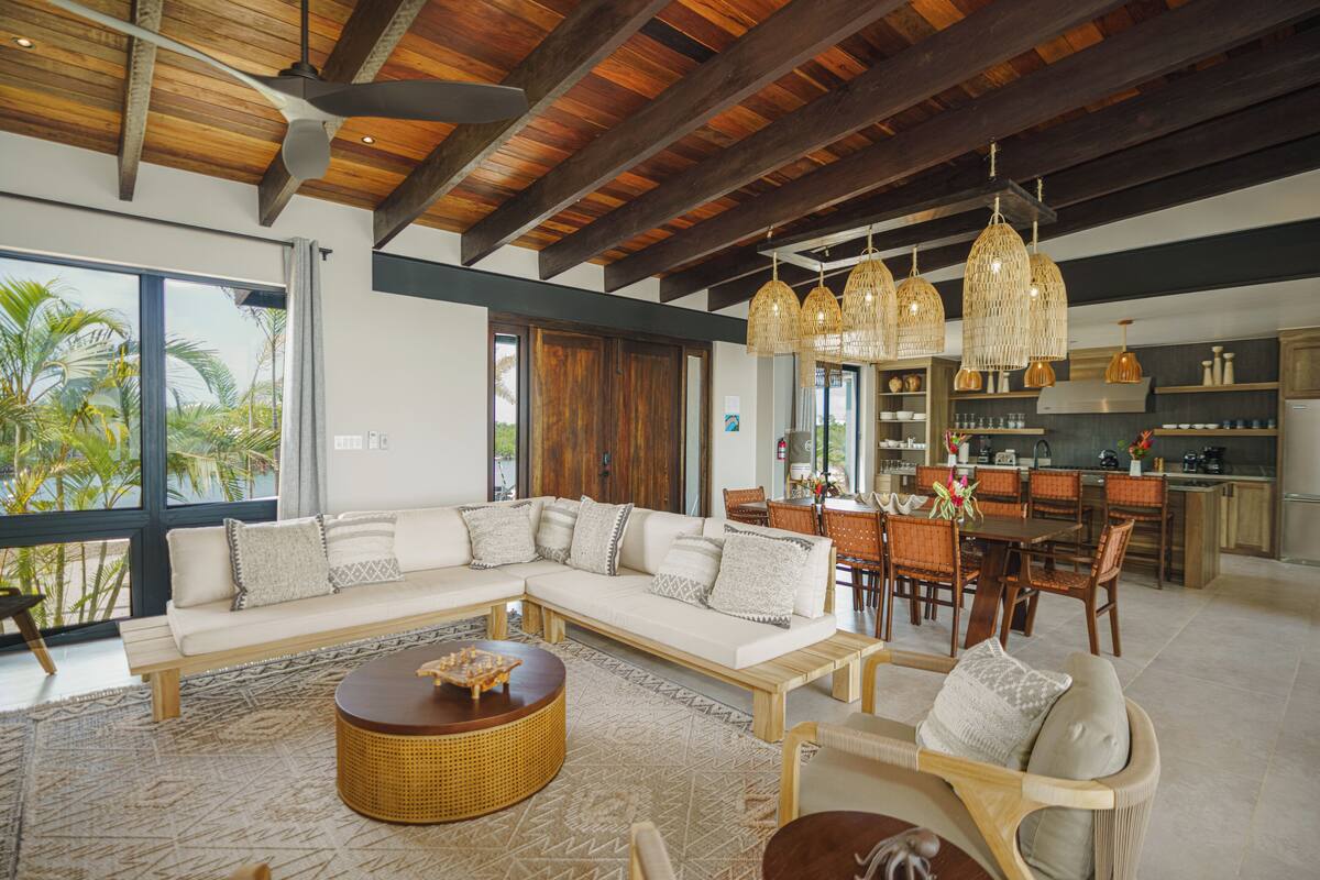 A spacious living area with a large sectional sofa, a round wicker coffee table, and a dining area with wooden chairs and a table.