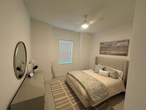 Relax in a cozy space with a comfortable bed, large mirror, and ceiling fan.