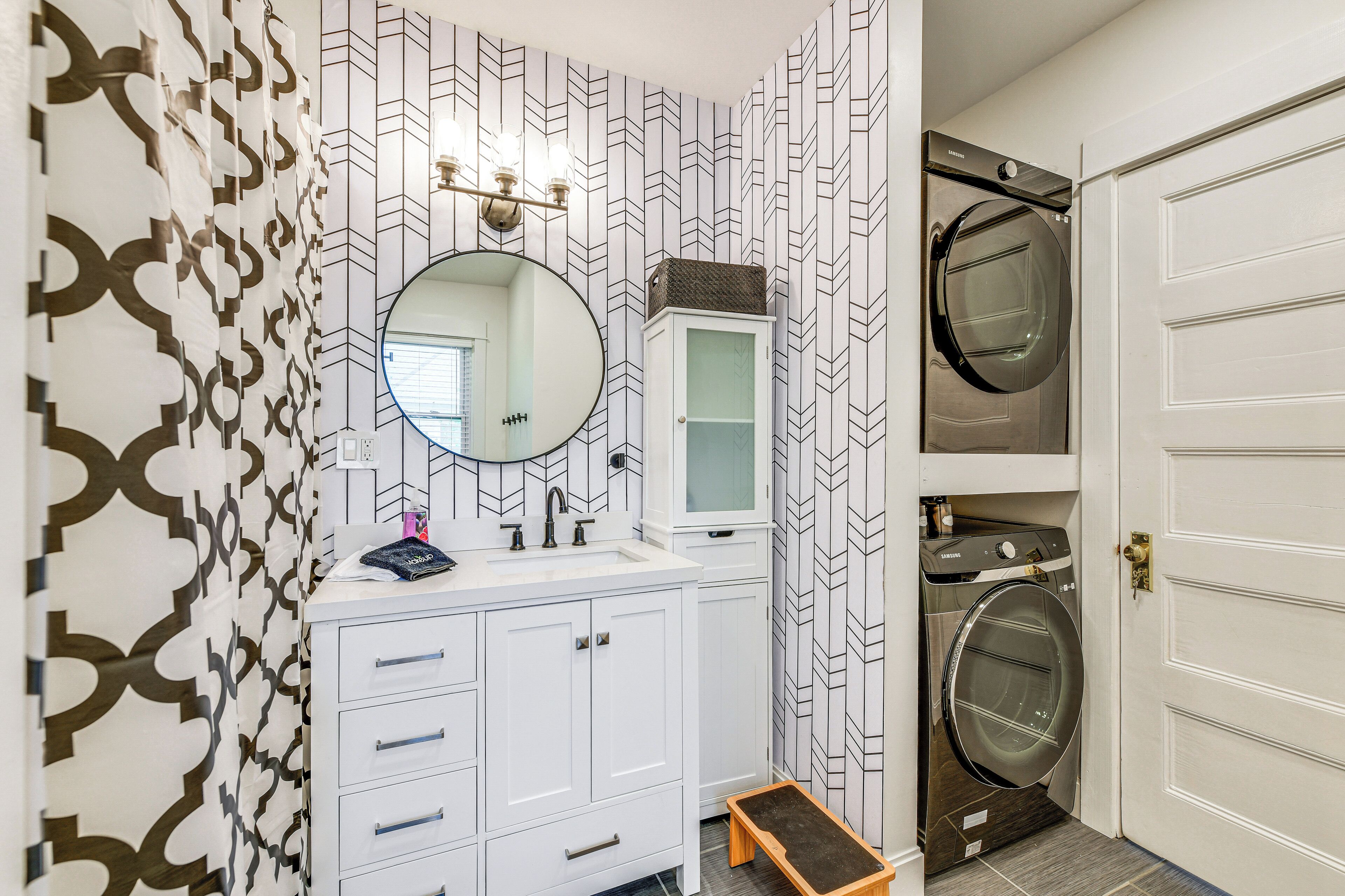 A bathroom with a white vanity, a mirror, a sink, and a built-in washing machine.