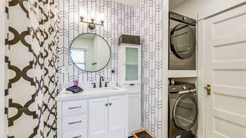 A bathroom with a white vanity, a mirror, a sink, and a built-in washing machine.