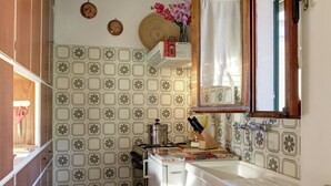A compact kitchen with patterned tiles, a sink, a stove, and a wooden cabinet. - Mansion on Fishermen's Isle (Stresa)