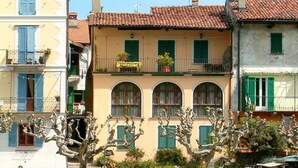 A building with a red-tiled roof, arched windows, and balconies with potted plants. - Mansion on Fishermen's Isle (Stresa)