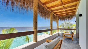 Une terrasse en bois offrant une vue sur l’océan, avec un banc et un fauteuil de relaxation.