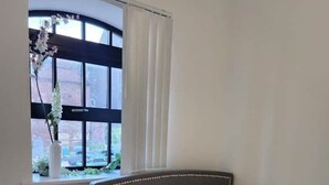 Une chambre à coucher avec un lit, une table de chevet, une lampe et une fenêtre avec des rideaux.