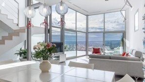 A modern living room with a large window, a dining area, and a staircase. - Villa Petrer in Javea X bia (Javea)
