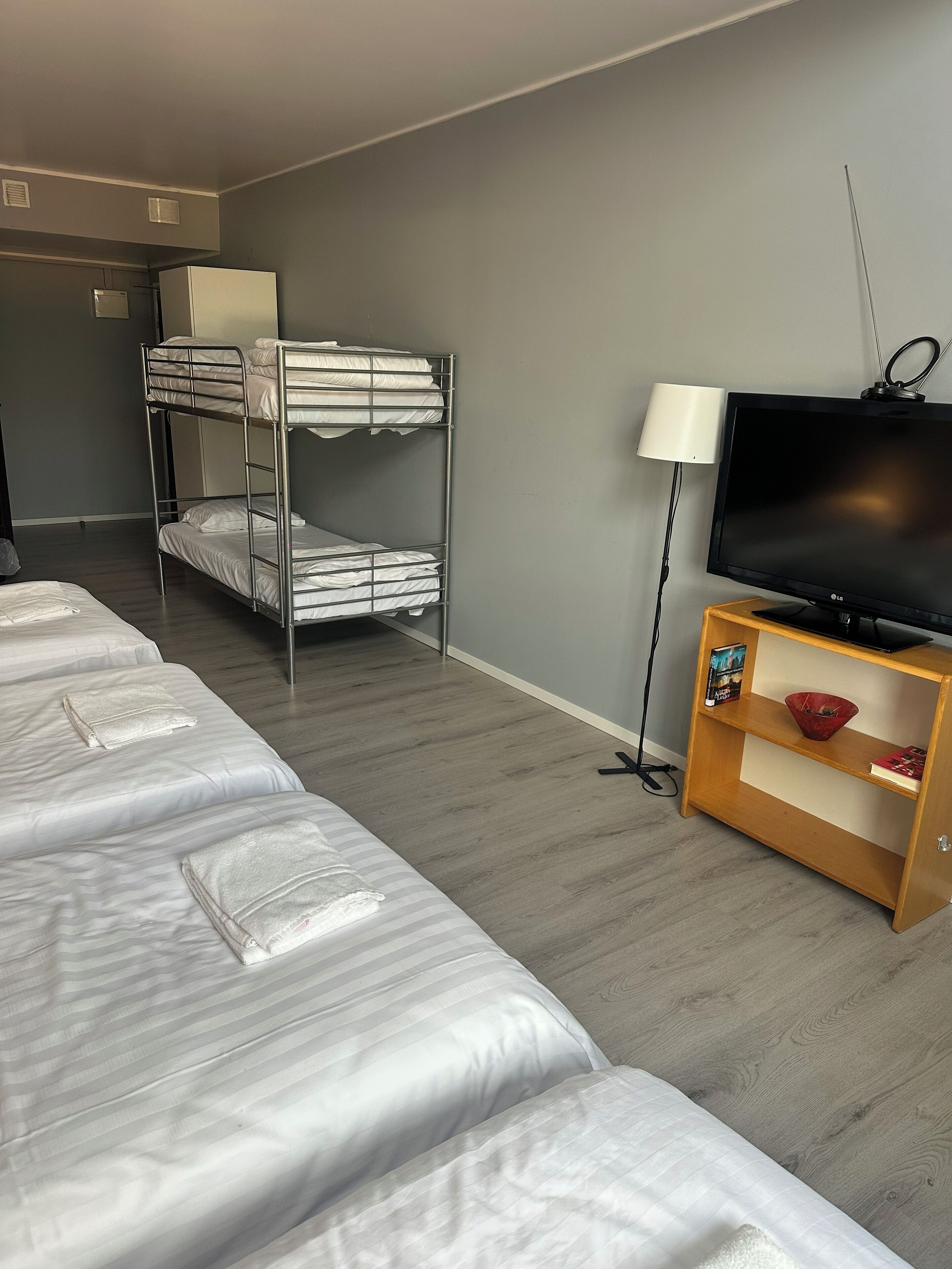 A hotel room with bunk beds, a television, and a wooden side table.