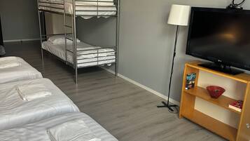 A hotel room with bunk beds, a television, and a wooden side table.
