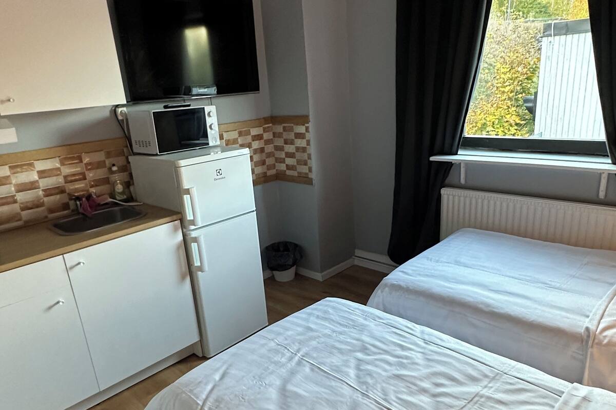 Quarto compacto com cozinha compacta, uma cama e janela com cortinas.