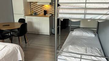 Una habitación compacta con literas, un kitchenette, una zona de comedor y una mesita pequeña.