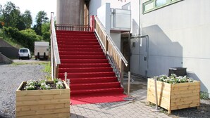 A staircase with red carpet leading to a building entrance. - Hotell Salem (Ronninge)