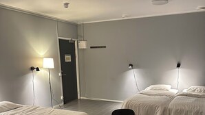 A hotel room with two single beds, a round table with chairs, and a small table with two remotes. - Hotell Salem (Ronninge)