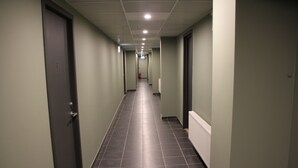 A long, narrow hallway with dark tiled floors and light green walls. - Hotell Salem (Ronninge)