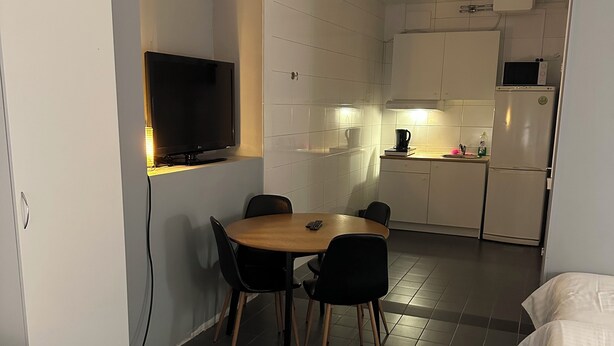 A compact hotel room with a dining area, kitchenette, and a bed. - Hotell Salem (Ronninge)