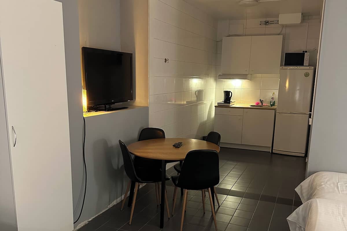 Quarto de hotel compacto com área de refeições, cozinha compacta e uma cama.