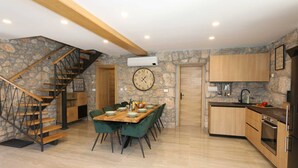 Une cuisine moderne avec une table et des chaises en bois, un four encastré et un mur en pierre.