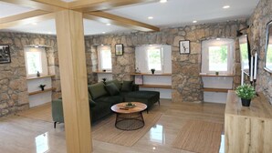 Un salon moderne avec un mur en pierre, un canapé vert, une table basse ronde et des étagères intégrées.