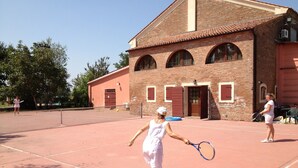 Un court de tennis avec un bâtiment en briques en arrière-plan.