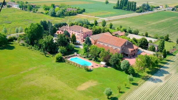 Une vue aérienne d’un vaste domaine comprenant plusieurs bâtiments, une piscine et de vastes étendues de verdure.