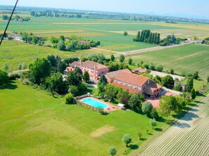 Vista aérea de una extensa propiedad con varias construcciones, piscina y amplios campos verdes.