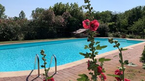 Une piscine avec une terrasse en briques et un escalier en métal.