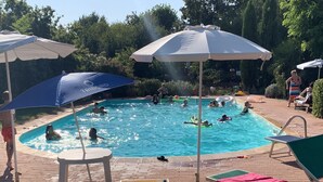 Zona de piscina con sillones de playa y sombrillas.