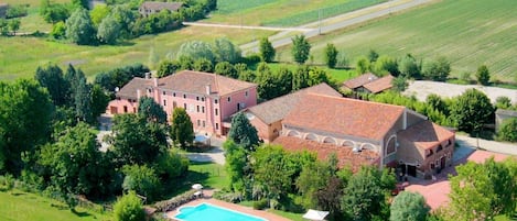 An aerial view of a large estate with multiple buildings, a swimming pool, and expansive green fields.
