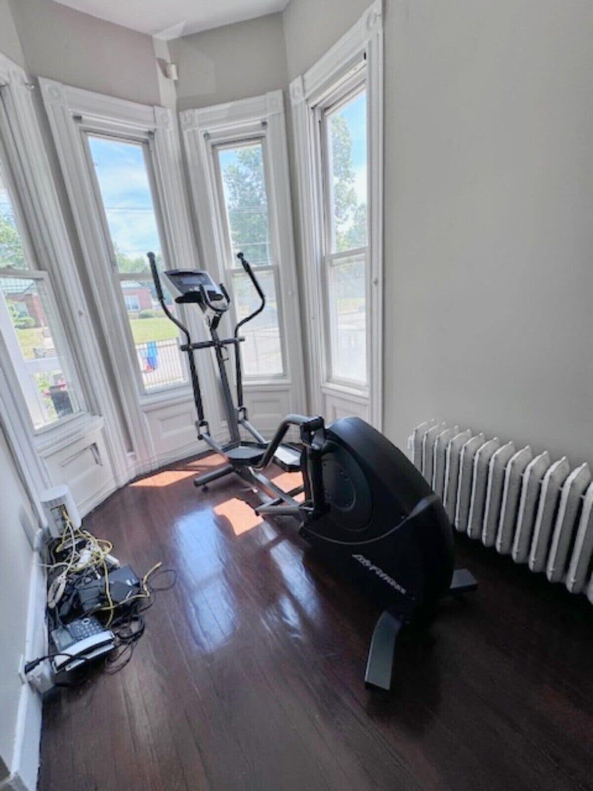 A room with a stationary bike, a treadmill, and a radiator.