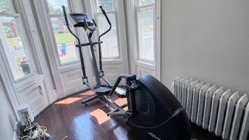 A room with a stationary bike, a treadmill, and a radiator.
