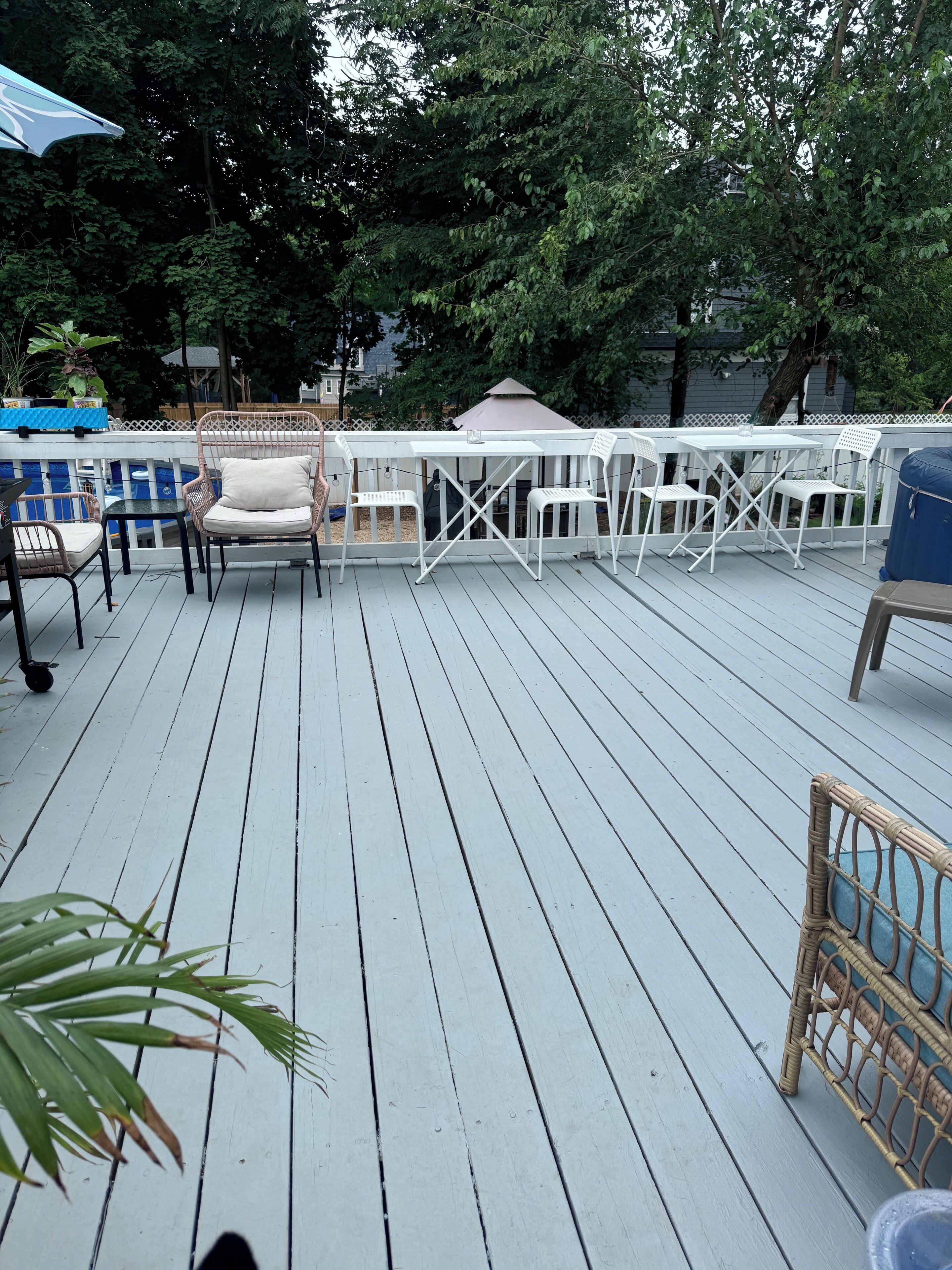 A wooden deck with white outdoor furniture, including chairs and a table.
