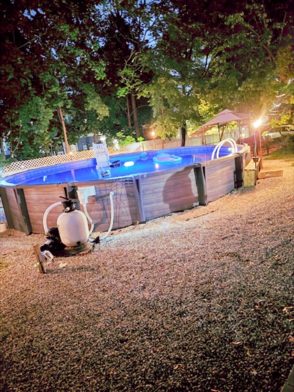 An outdoor swimming pool with a wooden deck and a hot tub.
