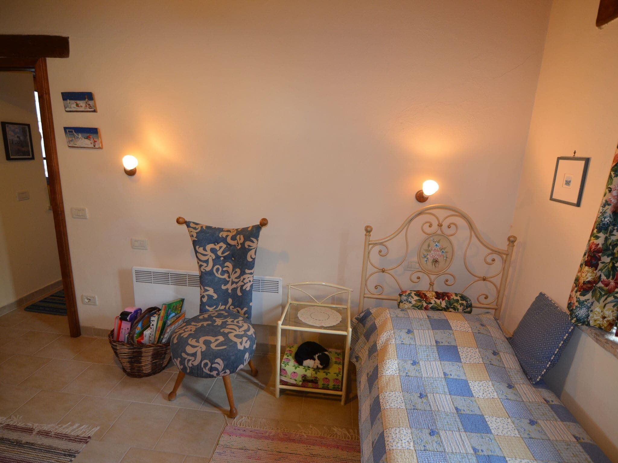 A bedroom with a bed, a chair, a small table, and a basket of items.