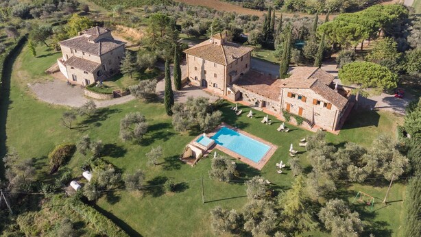 An aerial view of a large estate with multiple buildings, a swimming pool, and surrounding vineyards.