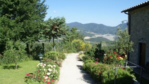 Un sendero en un jardín que lleva a un edificio de piedra con vistas a montañas.