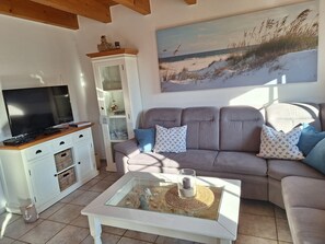 Relax in style with a comfortable sofa, flat-screen TV, and a beautiful beach scene painting.