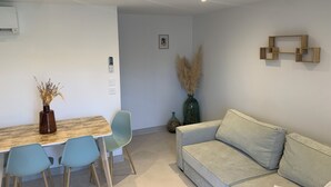 Ein modernes Wohnzimmer mit einem hellen Sofa, einem Holztisch und zwei hellblauen Sesseln. Auf dem Tisch steht eine dekorative Vase mit Pampasgras.