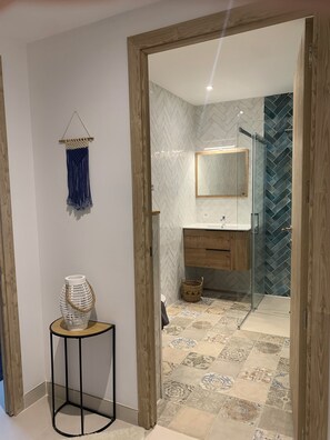 Un baño moderno con un salpicadero de azulejos en espiga, un box de ducha de vidrio y un mueble de tocador de madera.