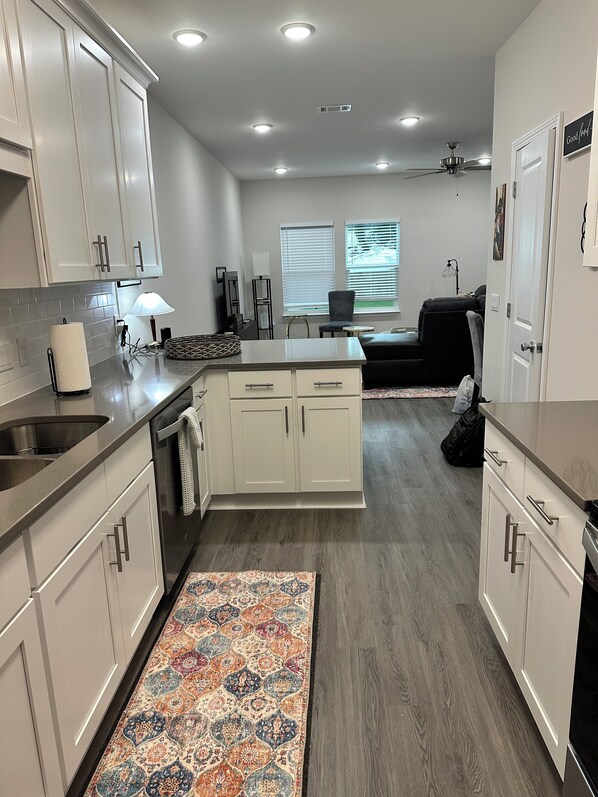 A modern kitchen with white cabinets, a central island, and a patterned rug.