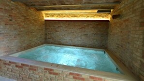 Un jacuzzi aux murs en briques, doté d’un plafond en bois et d’une lucarne.
