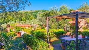 Un patio avec un jardin, une pergola, des sièges d’extérieur et des plantes en pot.