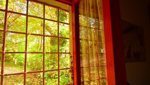 Una ventana con diseño de entramado que ofrece vistas a una zona boscosa.