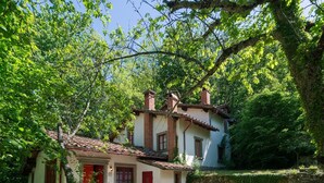 A rustic house with a tiled roof, a red door, and a patio with a wooden table and chairs. - Beautiful vacation home (Migliorini - Pistoia)