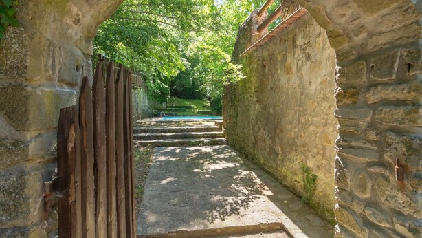 A stone archway leading to a pathway surrounded by greenery. - Beautiful vacation home (Migliorini - Pistoia)